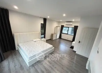 Spacious modern bedroom with sleek flooring and ample natural light