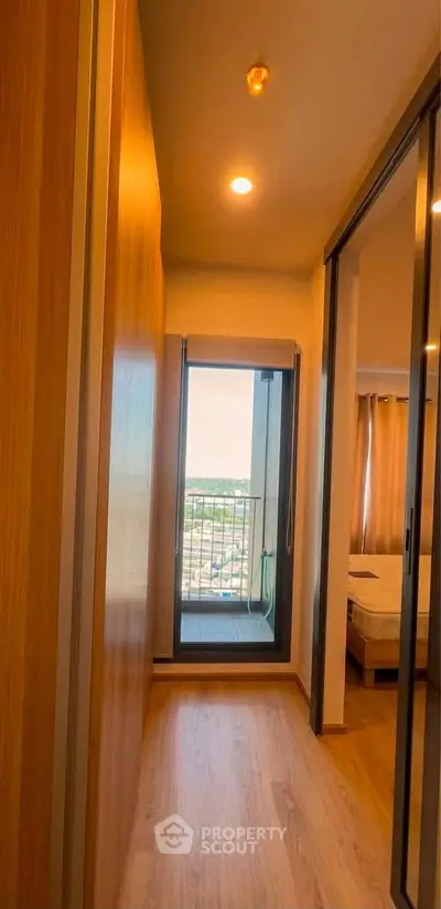 Bright hallway leading to a cozy bedroom with balcony view in modern apartment.