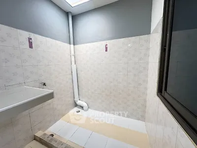 Spacious bathroom with modern tiles and natural light from skylight