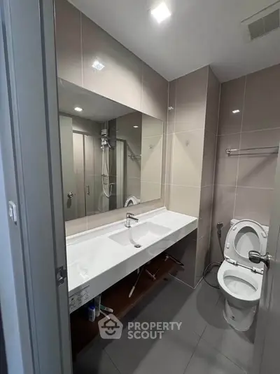 Modern bathroom with sleek fixtures and large mirror in contemporary apartment.
