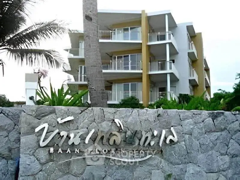 Modern multi-story building with lush landscaping and stone signage in front.