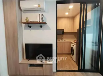 Modern apartment interior with kitchen and living area featuring TV and air conditioning.