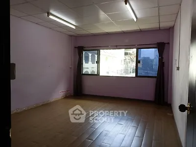 Spacious unfurnished room with large window and wooden flooring, ideal for customization.