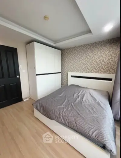 Modern bedroom with stylish wallpaper and sleek wardrobe in a contemporary apartment.