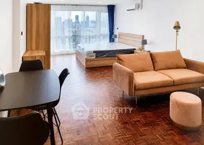Spacious studio apartment with city view, featuring modern furniture and parquet flooring.