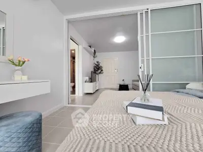 Modern bedroom with cozy decor and sliding glass doors leading to a bright living area.