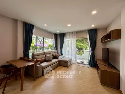 Spacious living room with modern decor and large windows opening to a balcony.