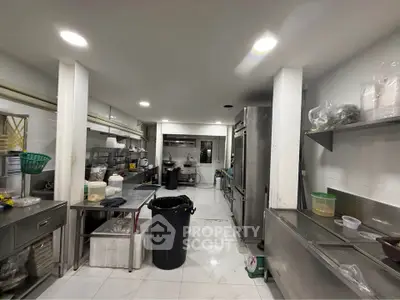 Spacious commercial kitchen with stainless steel appliances and ample storage space.
