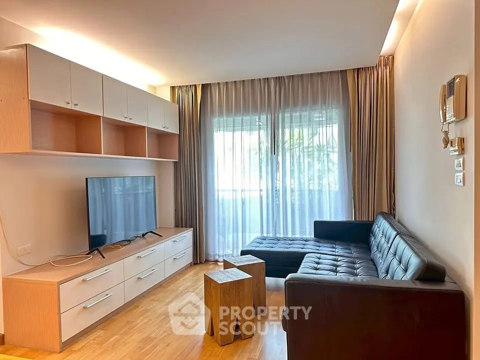 Modern living room with sleek furniture and natural light, featuring a stylish TV unit and cozy seating area.