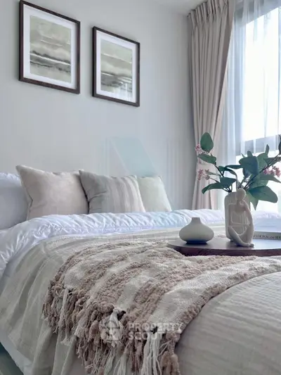 Elegant bedroom with cozy decor and natural light, featuring stylish bedding and framed artwork.