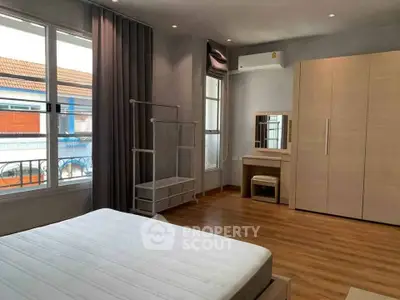 Spacious bedroom with modern furnishings and large window for natural light.