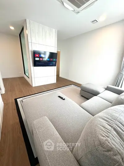 Modern living room with sleek design, featuring a large sectional sofa and wall-mounted TV.