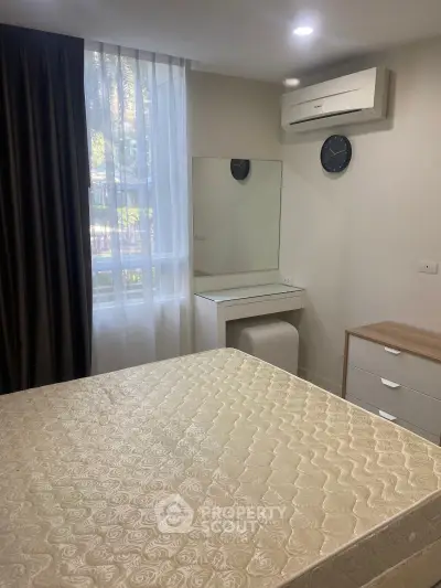 Cozy bedroom with air conditioning and natural light, featuring a stylish dresser and mirror.