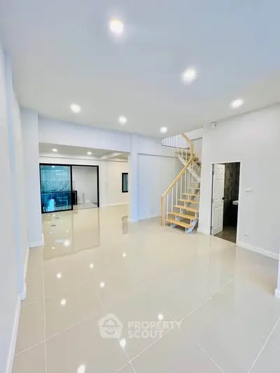 Spacious modern living room with sleek tile flooring and elegant staircase