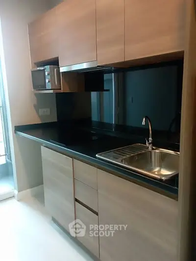 Modern kitchen with sleek cabinetry and stainless steel sink in a contemporary apartment.