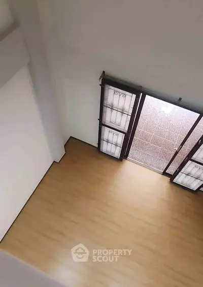 Spacious empty room with wooden flooring and large windows for natural light.