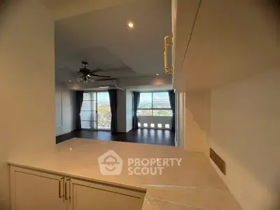 Spacious living room with large windows and modern ceiling fan, offering a bright and airy atmosphere.