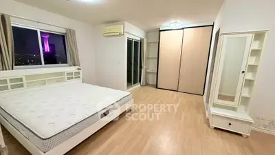 Spacious bedroom with city view, featuring a large bed and ample storage space.