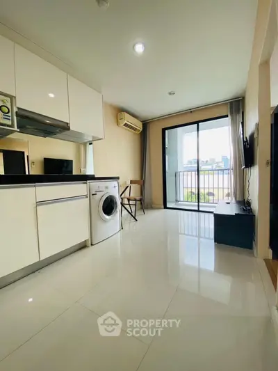 Modern apartment with sleek kitchen and balcony view, featuring washing machine and open layout.