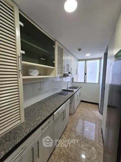 Modern kitchen with granite countertops and ample storage in a sleek apartment.