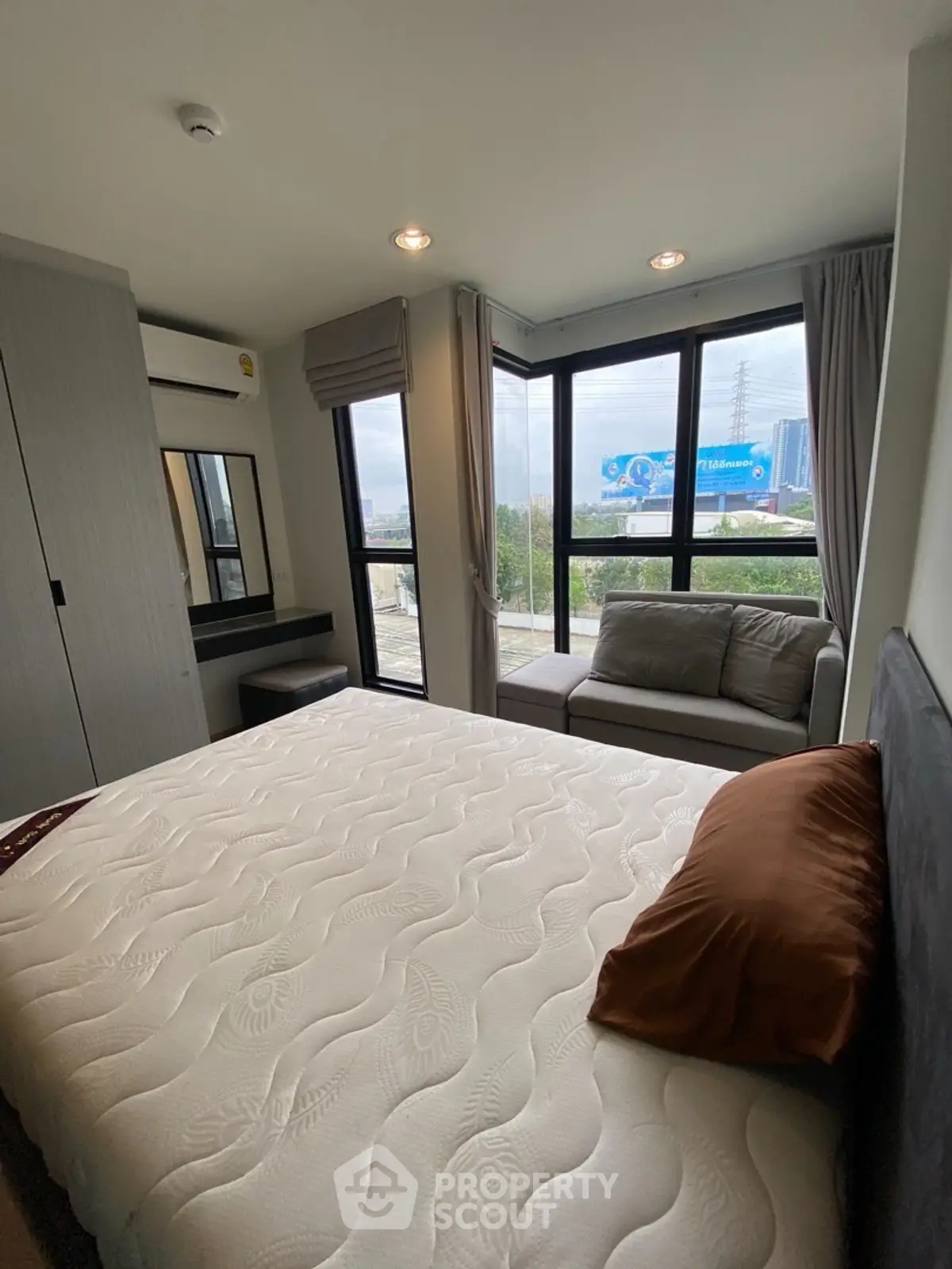 Modern bedroom with large windows and cozy sofa, offering a bright and inviting atmosphere.