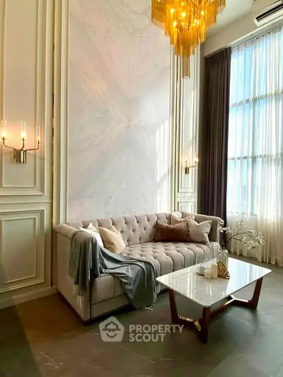 Luxurious living room with elegant chandelier and plush sofa in high-rise apartment.