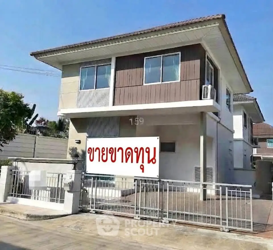Modern two-story house with gated entrance and contemporary design.