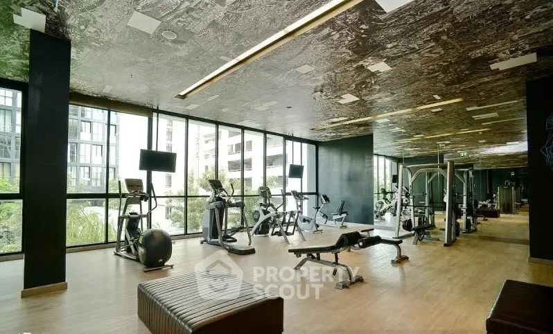 Modern gym with state-of-the-art equipment and floor-to-ceiling windows in luxury building.