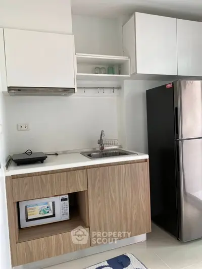 Modern compact kitchen with sleek cabinetry and stainless steel fridge