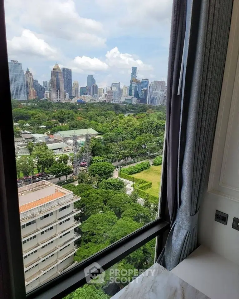 Stunning cityscape view from high-rise apartment window overlooking lush green park.