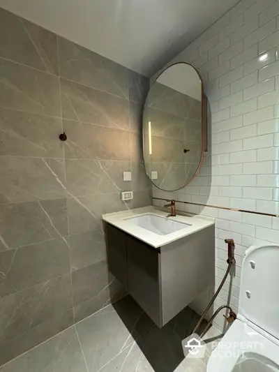 Modern bathroom with sleek design, featuring a round mirror and elegant fixtures.