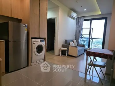 Modern apartment interior with kitchen and living room, featuring washing machine and city view.
