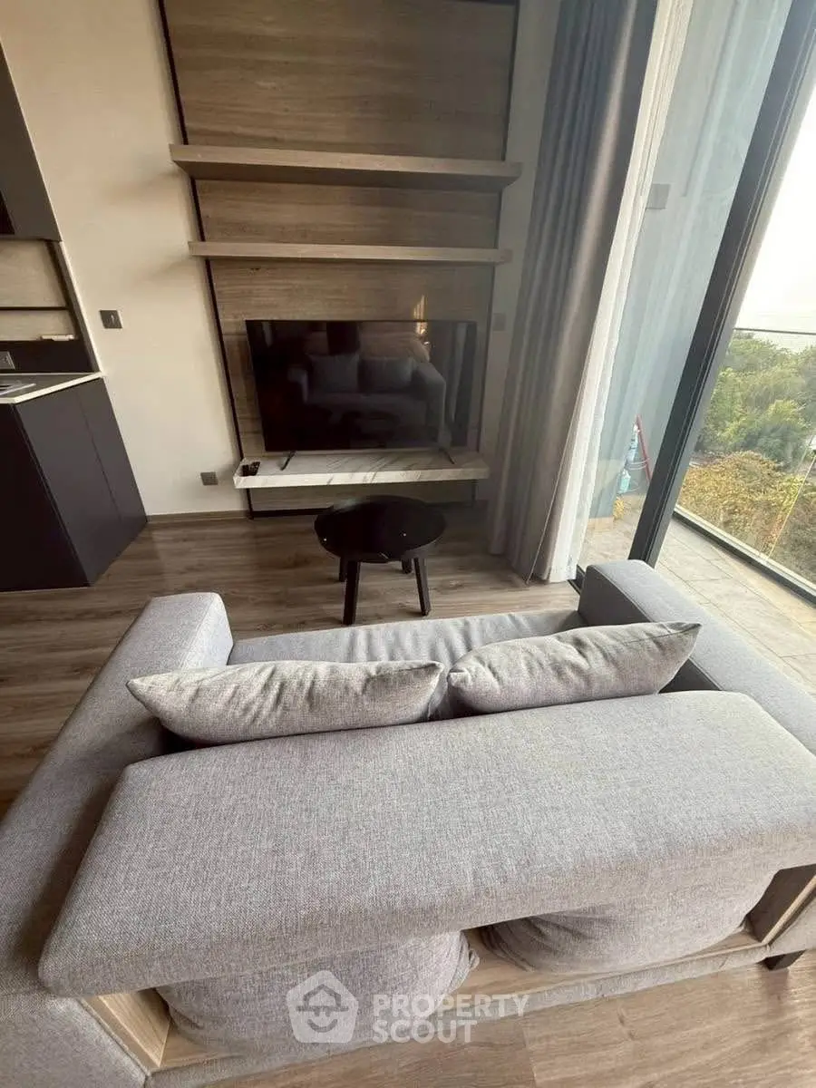 Modern living room with sleek furniture and large window offering stunning views.