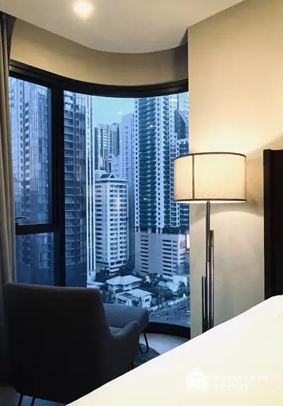 Luxurious bedroom with stunning city view from high-rise apartment window.