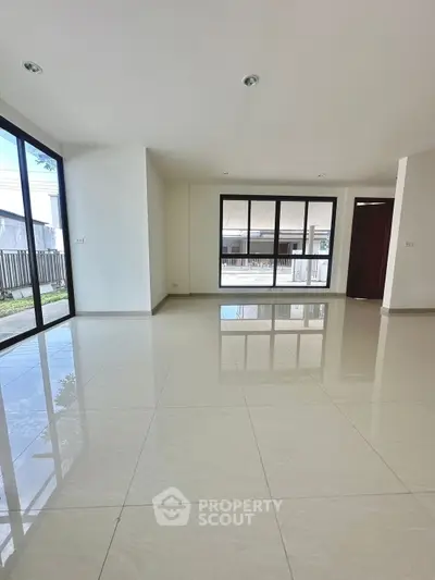 Spacious modern living room with large windows and glossy tiled floors
