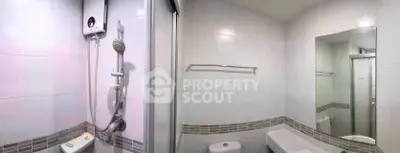 Modern bathroom with shower and bathtub in sleek white tiles.