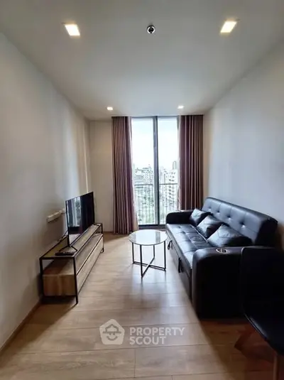 Modern living room with sleek furniture and city view through large window.