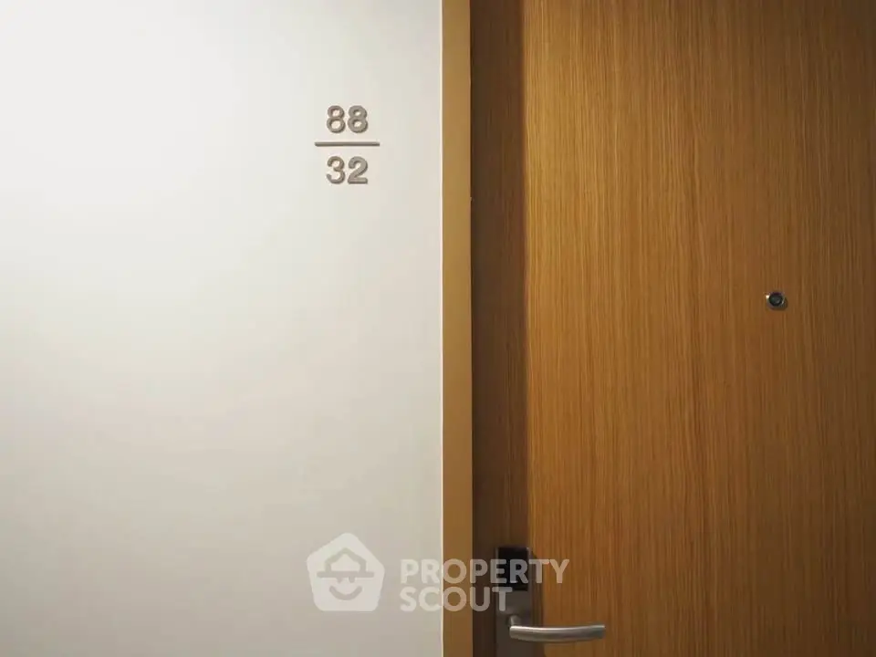 Modern apartment door with sleek wooden finish and room number displayed on wall.