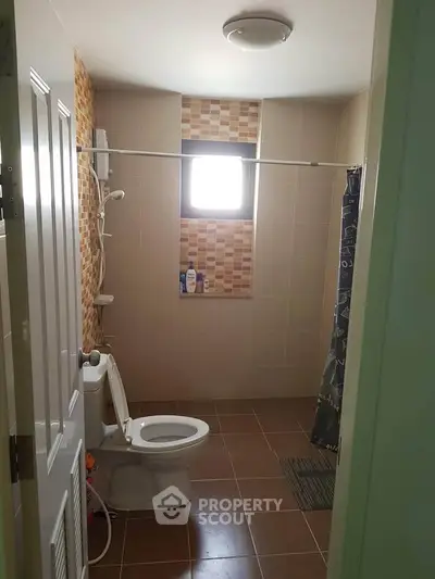 Modern bathroom with tiled walls and window, featuring a shower and toilet.
