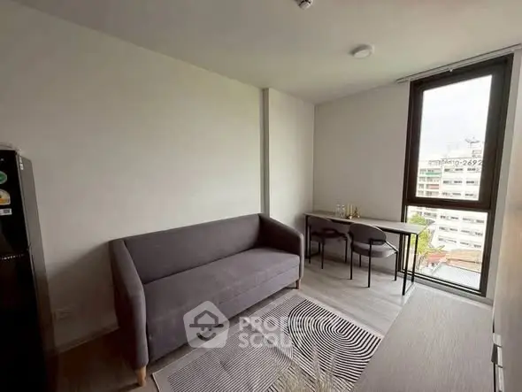 Modern living room with sleek gray sofa and dining table, featuring large window with city view.
