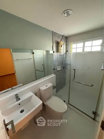 Modern bathroom with sleek fixtures and glass shower enclosure in a contemporary home.