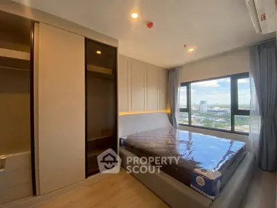 Modern bedroom with large window and city view, featuring sleek built-in wardrobe.