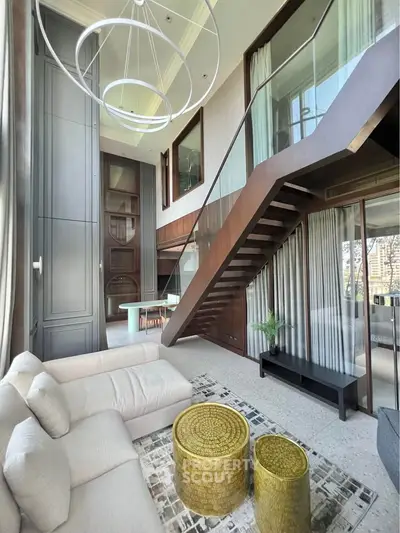 Luxurious modern living room with high ceilings and elegant staircase in a stylish duplex apartment.