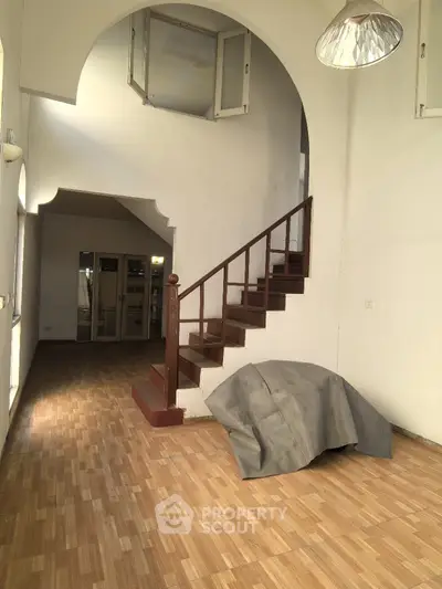 Spacious interior with wooden staircase and high ceilings, perfect for renovation.