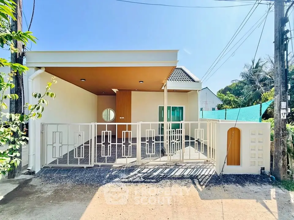 Modern single-story house with gated entrance and spacious driveway in a sunny neighborhood.