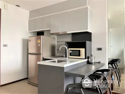 Sleek modern kitchen with stainless steel appliances, ample cabinetry, and a convenient breakfast bar in a bright, airy space.