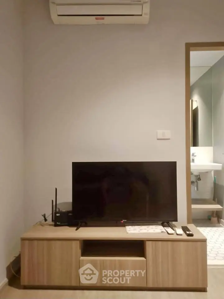 Modern living room with sleek TV setup and air conditioning unit, perfect for cozy entertainment.