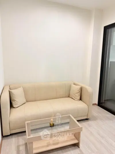 Modern living room with beige sofa and glass coffee table in a cozy apartment.