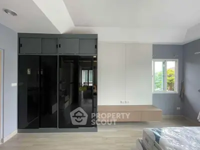 Modern bedroom with sleek black wardrobe and natural light