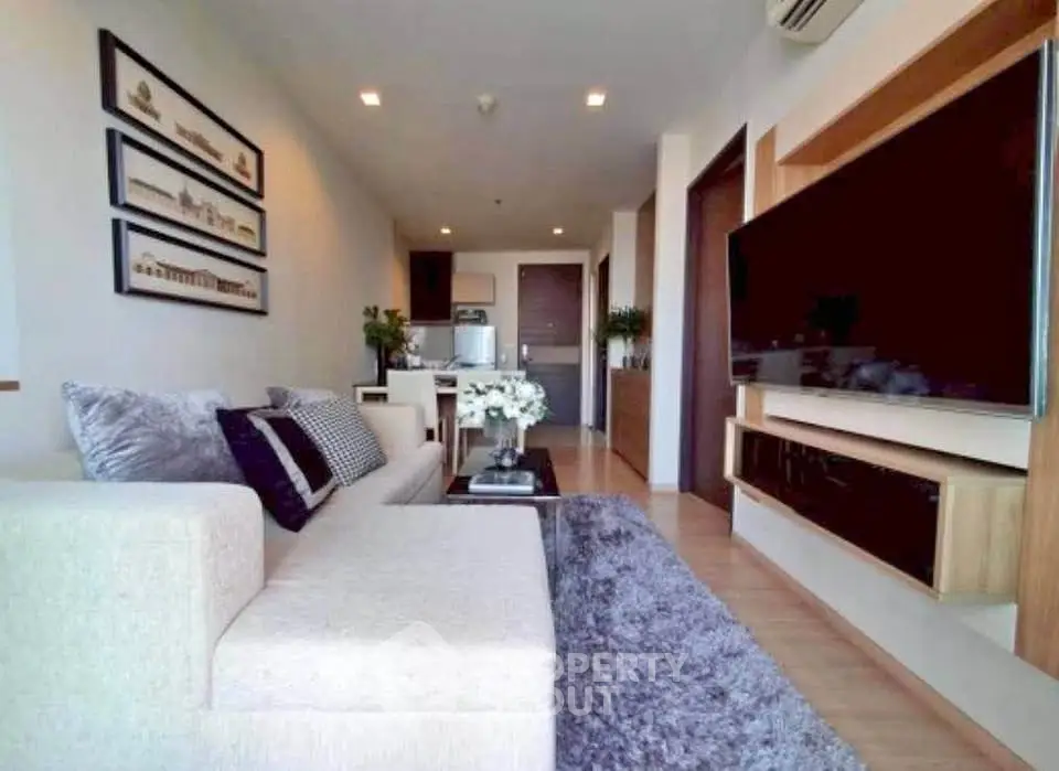 Modern living room with stylish decor and large TV in a cozy apartment setting.